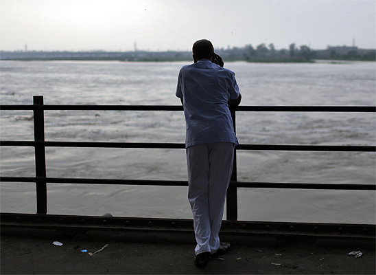 A man stands under a bridge built over river Yamuna in New Delhi