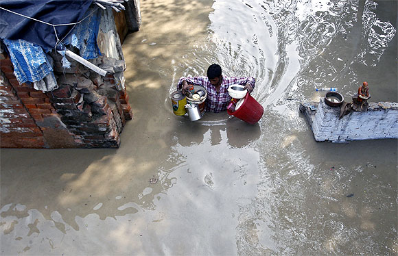 A resident carries his belongings through an alley flooded with the rising water level of river Yamuna after heavy monsoon rains in New Delhi