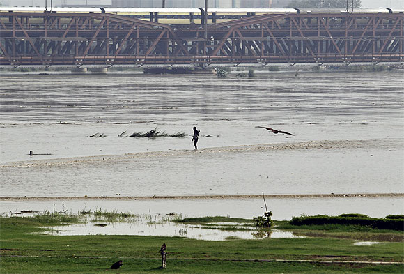 A man stands on the banks of the flooded river Yamuna after heavy monsoon rains in New Delhi