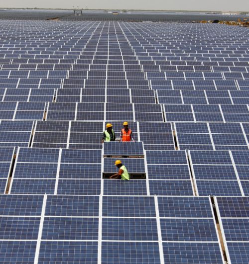 Workers install photovoltaic solar panels at the Gujarat solar park under construction in Charanka village in Patan district.