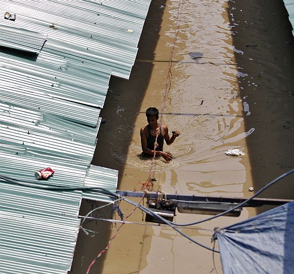 A man wades through a flooded alley at a shopping arcade after heavy monsoon rains caused the rise in waters of Yamuna