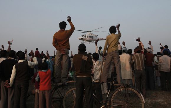 Villagers wave towards a political leader's helicopter