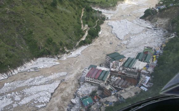 Flood waters flow next to a residential complex in Uttarakhand