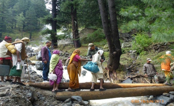 Army personnel evacuate people across a rivulet by laying a temporary bridge made of wooden logs on rout in Uttarakhand