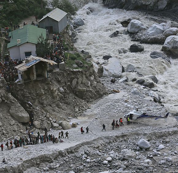 Soldiers assist survivors to board a rescue helicopter next to the River Alaknanda