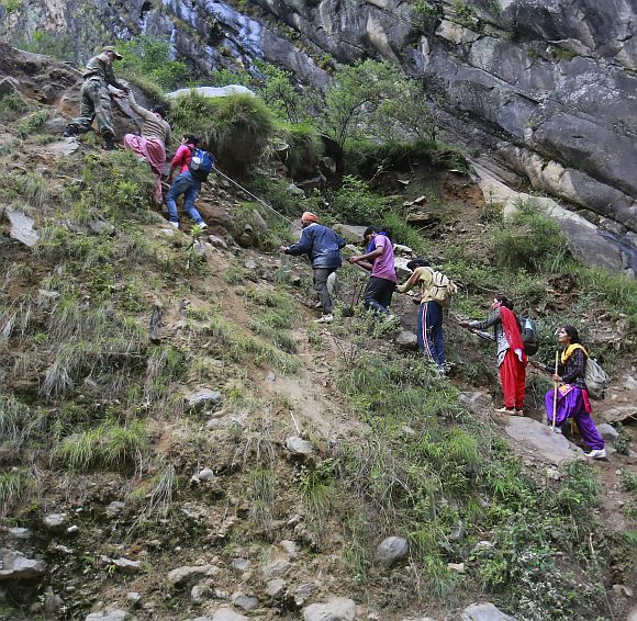 Pilgrims are helped to climb over a hill by Army soldiers during a rescue operation at Govindghat