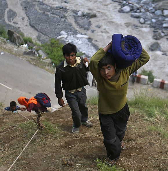 A boy carrying a bundle on his shoulder climbs over a hill during a rescue operation at Govindghat