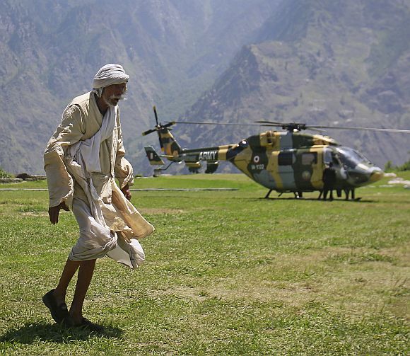A man walks across a field after alighting from an army helicopter