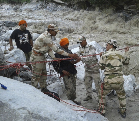 The Indo-Tibetan Border Police (ITBP) personnel rescue stranded people across a flooded river after heavy rains in the Himalayan state of Uttarakhand