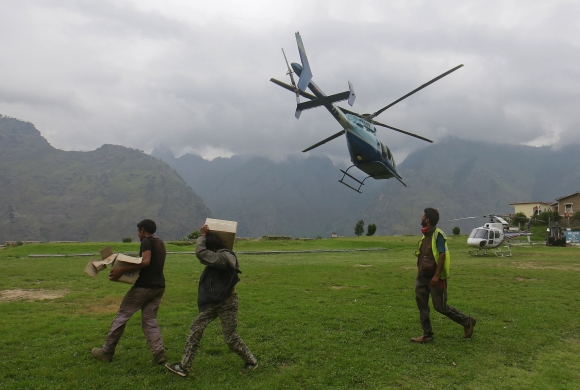  Soldiers carry boxes of relief supplies as an army helicopter flies overhead during a rescue operation at Joshimath