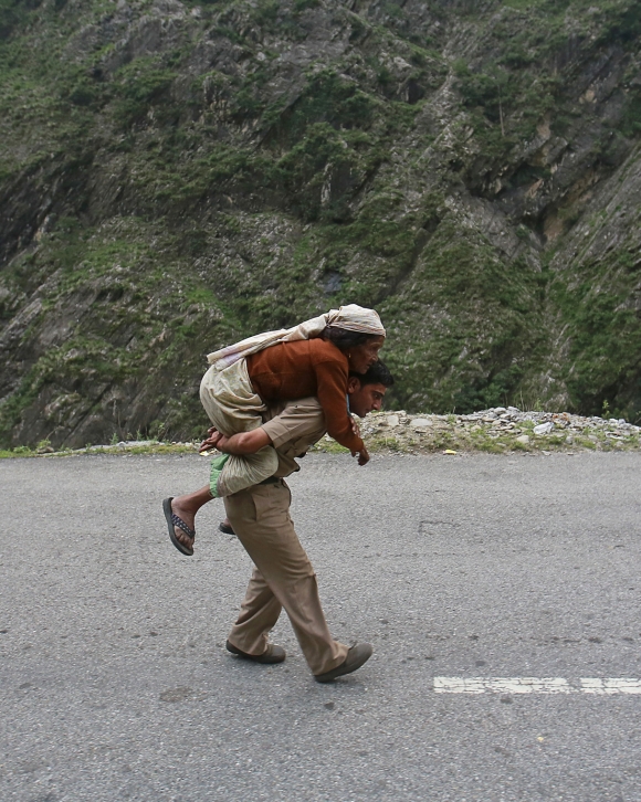 A policeman carries an old woman on his back during rescue operations in Govindghat