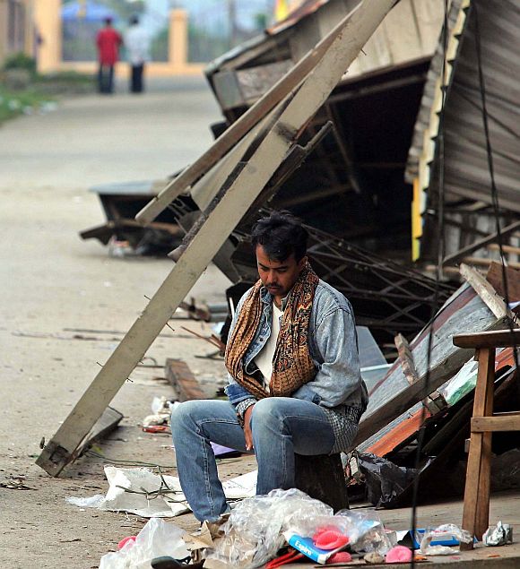 A man sits outside a damaged house after the massive earthquake