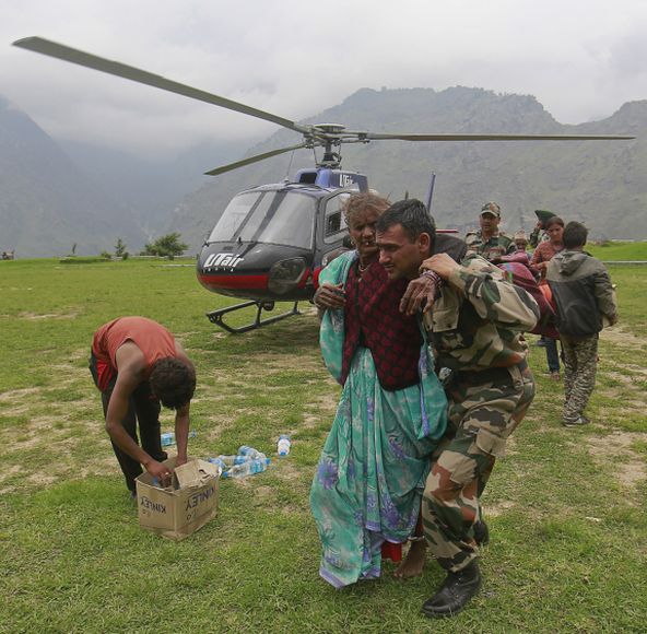 A woman is assisted by a soldier as she leaves an army helicopter during a rescue operation at Joshimath in the Himalayan state of Uttarakhand