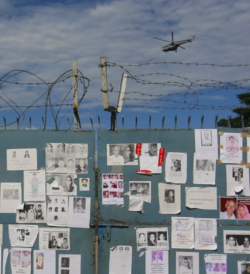 Posters of missing people, caused by the flash floods and landslides, are placed on a gate as an IAF helicopter lands at a base in Dehradun