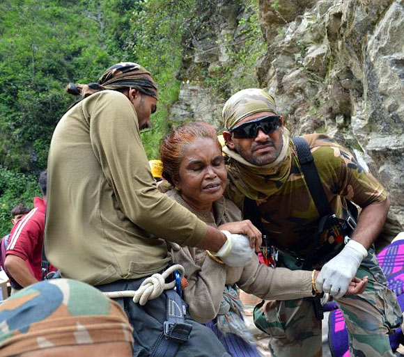 A frail woman being helped to safety In Uttarakhand
