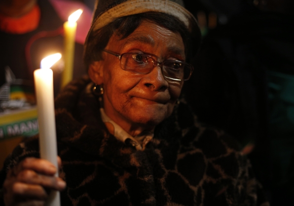 A woman holds a candle in support of ailing Mandela outside his former home in Soweto