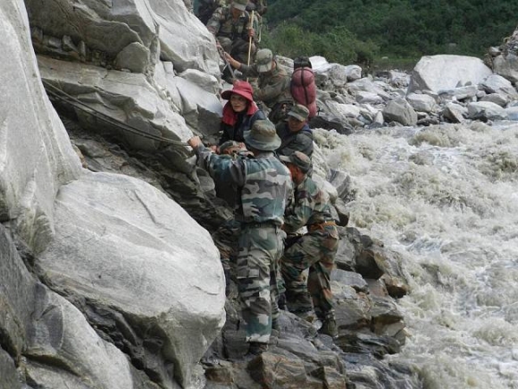 Army men help rescue a tourist who was stranded for weeks following the floods