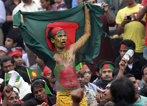 A man holds a Bangladesh national flag as he chants a slogan before a mass funeral as the body of Rajib Haider, an architect and blogger who was a key figure in organising demonstrations, arrives at Shahbagh intersection in Dhaka