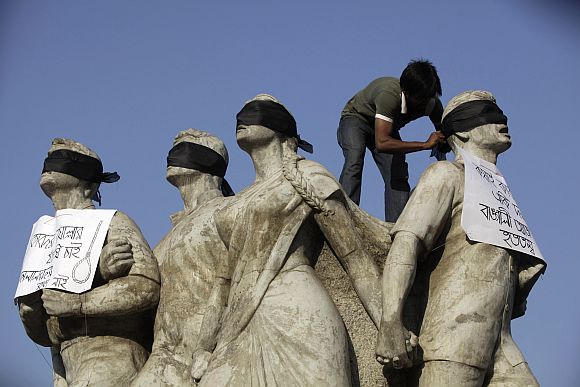 A student activist puts black scarves on the eyes of Shoparjito Shadhinota, a sculpture that represented all sections of people in Bangladesh's liberation War in 1971, demanding capital punishment for Bangladesh's Jamaat-e-Islami senior leader Abdul Quader Mollah