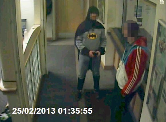 A man dressed as Batman and a burglary suspect stand in a police station in Bradford, northern England, on February 25, 2013, in this photograph taken from a CCTV video.