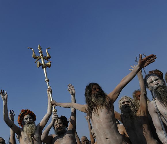 Sadhus gesture as one of them holds a trishul or trident-shaped weapon after taking a dip during the second Shahi Snan (grand bath), of the ongoing Kumbh Mela