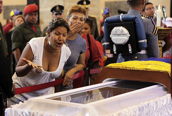 Supporters of the late Venezuelan President Hugo Chavez react as they view his coffin during a wake at the military academy in Caracas