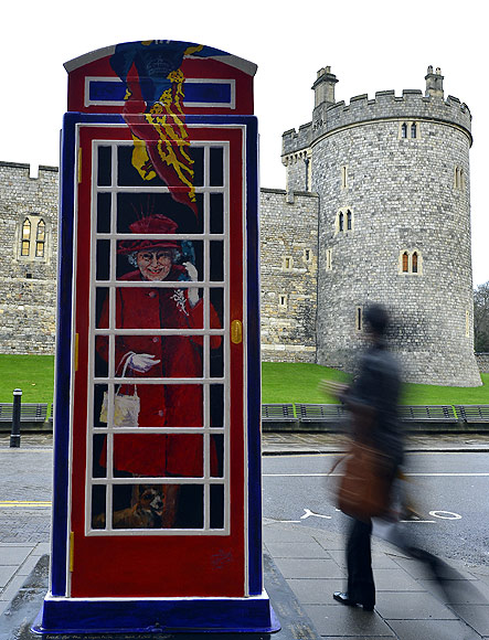 A pedestrian passes a painted image of Britain's Queen Elizabeth outside Windsor Castle in Windsor, southern England