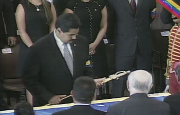 TV grab shows Vice President Nicolas Maduro holding a replica of the Simon Bolivar's sword as he stands over the coffin of Hugo Chavez, during the funeral at the military academy in Caracas.