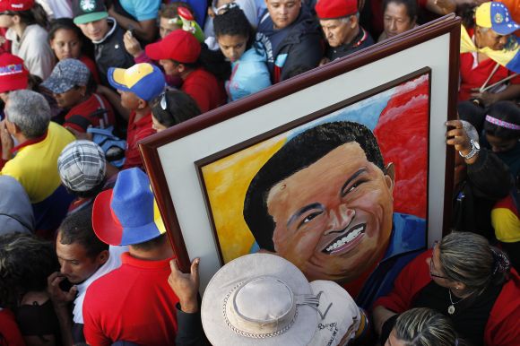 Supporters of Hugo Chavez hold a portrait of him near the military academy in Caracas on Friday