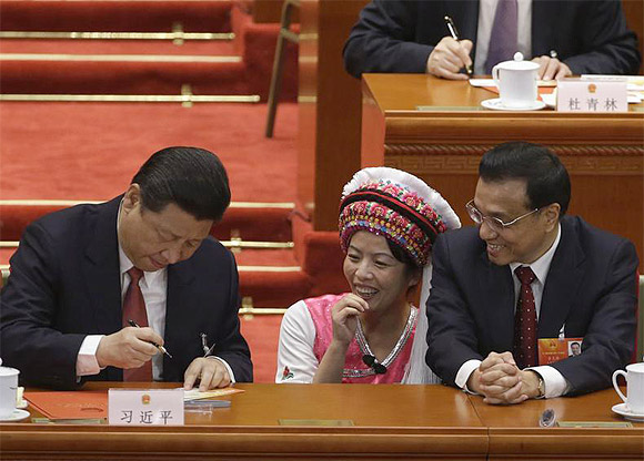 China's Vice-Premier Li Keqiang and an ethnic minority delegate look at Xi Jinping signing an autograph for the delegate during the fourth plenary meeting of National People's Congress