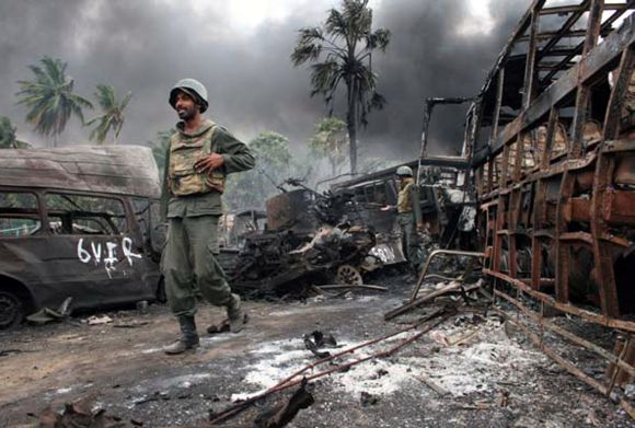 File photo shows Sri Lankan troops walking near burnt or burning vehicles in the area inside the war zone near the town of Mullaittivu