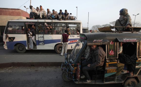 A vendor tries to sell bananas to the passengers sitting atop of a bus as they wait to cross a toll gate at Hajipur industrial park on the outskirts of the eastern Indian city of Patna, in Bihar