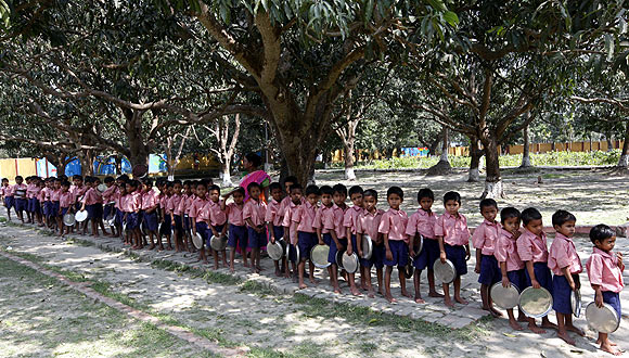 Children queue up to collect their free mid-day meal distributed by a non-governmental organisation inside a school in Kolkata.
