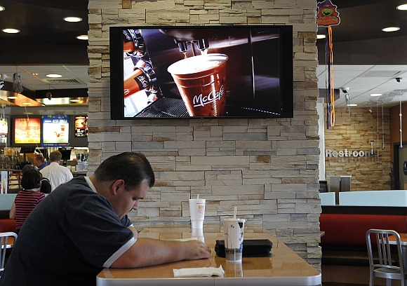 Customer Steven Price sits at a table near a HDTV screen showing the new McDonald's Channel featuring a commerical about McCafe drinks at a McDonald's restaurant, part of the test market for the channel in Norwalk, California
