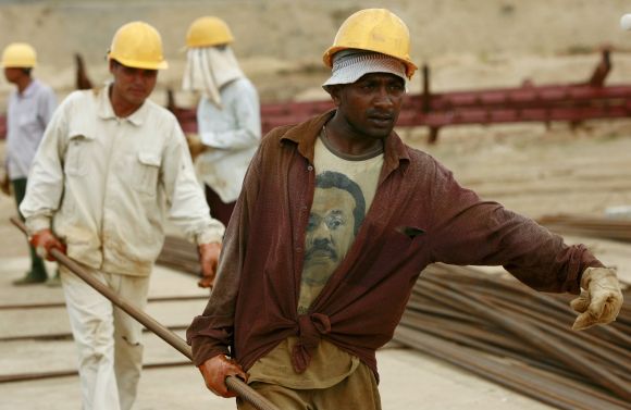 A Sri Lankan worker carries an iron bar with Chinese workers at the construction site for the now operational shipping port in Hambantota.