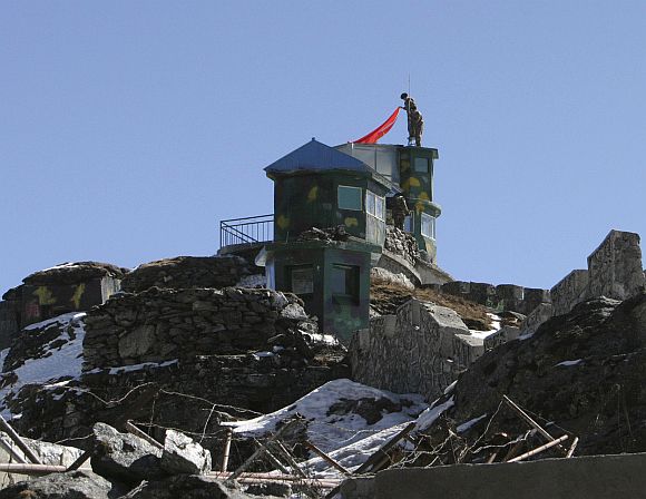 Chinese soldiers put up a flag atop their border post