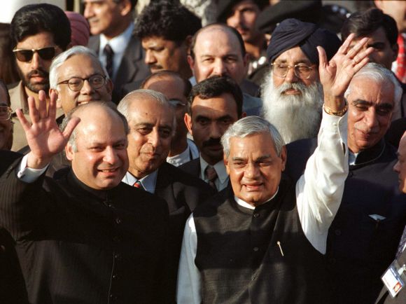 Former Pakistan prime ministers Nawaz Sharif (L) and his Indian counterpart Atal Behari Vajpayee (R) wave to a crowd at Wagah border near Lahore