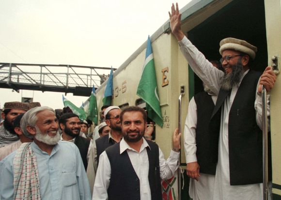 Sayed Munawar Hassan, acting chief of the religious Jama'at-i-Islami (JI) party, waves to supporters at Rawalpindi railway station