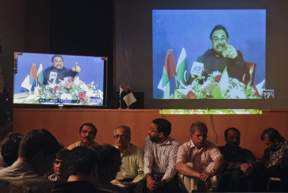 Supporters of Muttahida Qaumi Movement surround television screens broadcasting a speech by their party leader Altaf Hussain from London via video conference in Karachi