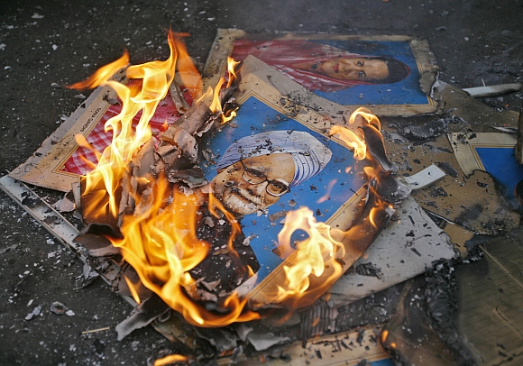 Portraits of Prime Minister Manmohan Singh and  Congress president Sonia Gandhi lie in flames after they were set alit by the demonstrators during a protest in Ahmedabad