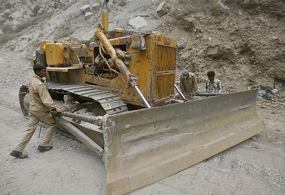 Labourers employed by the Indian army, adjust a bulldozer blade on India's Tezpur-Tawang highway which runs to the Chinese border in Arunachal Pradesh