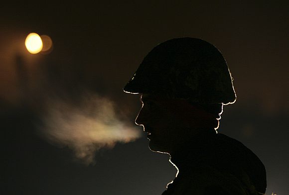 A soldier keeps vigil during night patrol near the fenced border with China