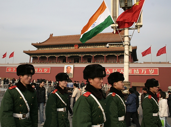Chinese policemen walk past an Indian flag in front of Tiananmen Gate in Beijing