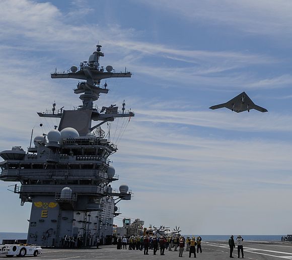 An X-47B Unmanned Combat Air System demonstrator flies over the aircraft carrier USS George HW Bush
