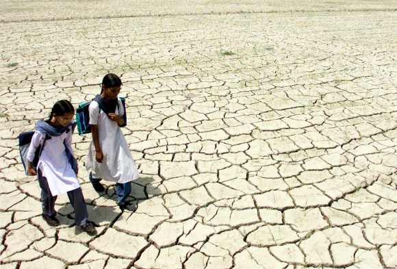 Two Indian students walk through a dry paddy field in Raipur village in Punjab