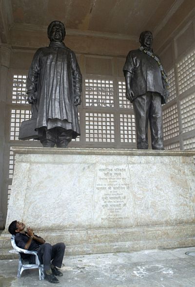 A security guard sits in front of bronze statues of Mayawati and Kanshi Ram, founder of the Bahujan Samaj Party, in Lucknow