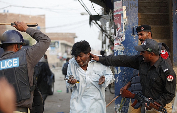 Police beat and detain a Pakistani Christian protester during a demonstration in Badami Bagh, Lahore
