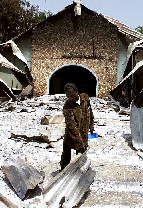 Nigerian James Alkali searches through the burnt remains of the Church of Christ, February 27, 2004, in which 48 Christians were massacred in Yelwa, Plateau state in central Nigeria