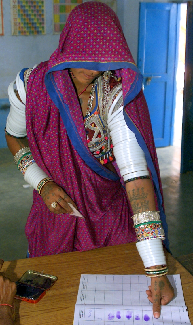A woman registers her thumb impression to cast her ballot inside a polling booth at Aakarabhatta village in Rajasthan during the last state elections