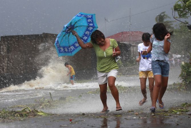 Residents walk along the coastal village while strong winds from Typhoon Haiyan battered Bayog town in Los Banos, Laguna, south of Manila, on Friday